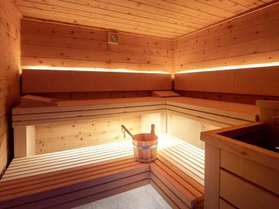 Sauna in legno con secchio e mestolo, illuminazione calda.