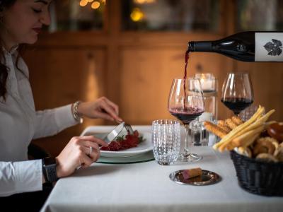 Frau beim Abendessen mit Rotwein und Essen auf einem eleganten Tisch.