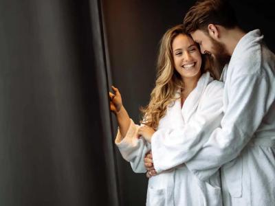 Happy couple in bathrobes embracing near a window.