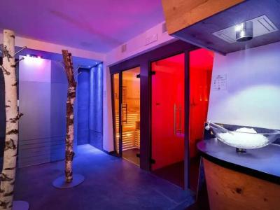 Modern spa with sauna and shower, colorful lighting.