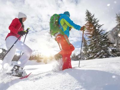 Zwei Personen wandern im Schnee mit Schneeschuhen.