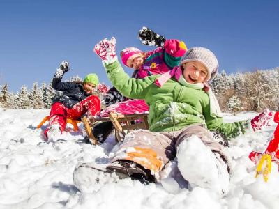 Kinder spielen im Schnee mit Schlitten und haben Spaß an einem Wintertag.