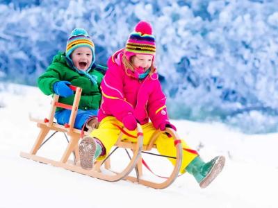 Happy children sledding on the snow in winter.