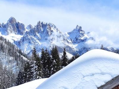 Snowy mountains and wooden chalet under a blue sky.