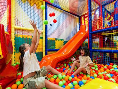 Bambini giocano felici in una piscina di palline colorate.