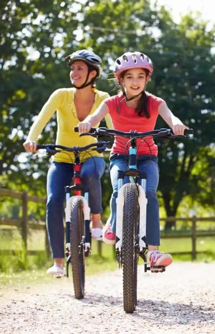 Familie fährt Fahrrad auf einem Weg, sonniger Tag.