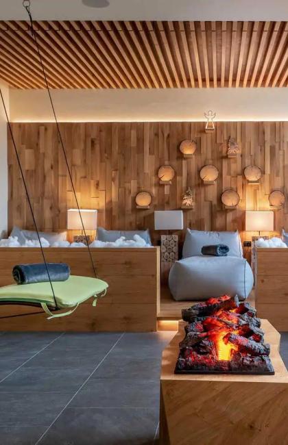 Sala relax con sedie a sdraio, focolare e decorazioni in legno.