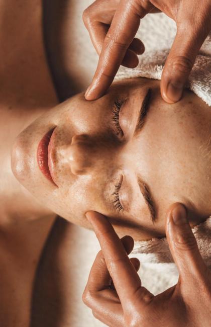 Person receiving a relaxing facial massage with a towel on their head.