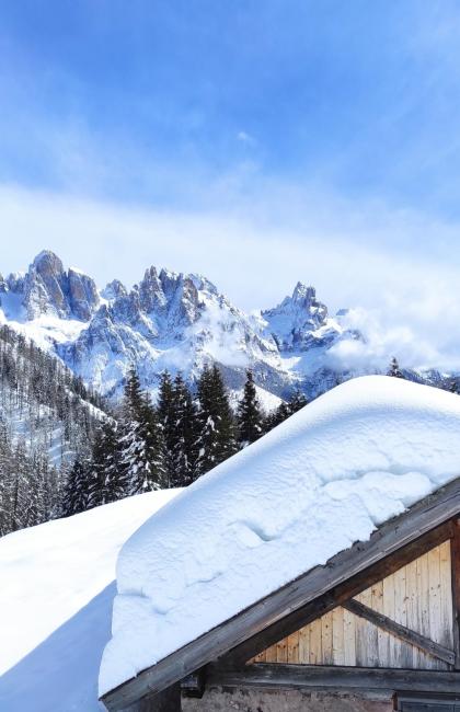 Verschneite Berge und Holzchalet unter blauem Himmel.