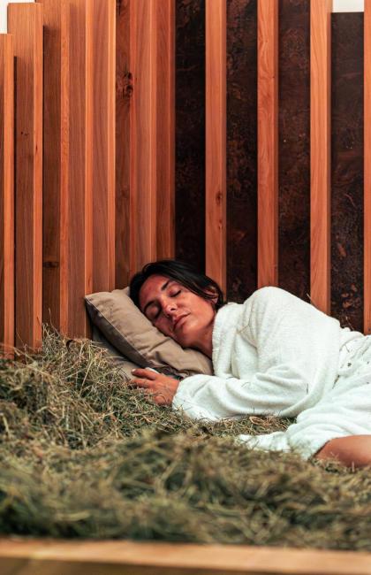 Woman sleeping on a hay bed in a wooden room.