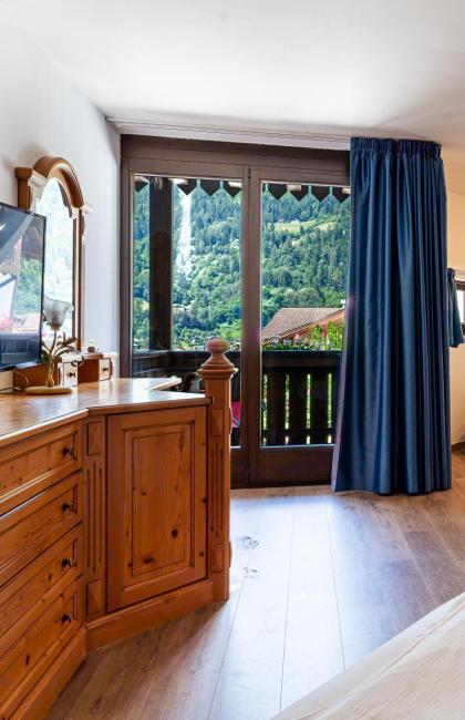 Cozy room with mountain view, wooden furniture, sofa, and balcony.