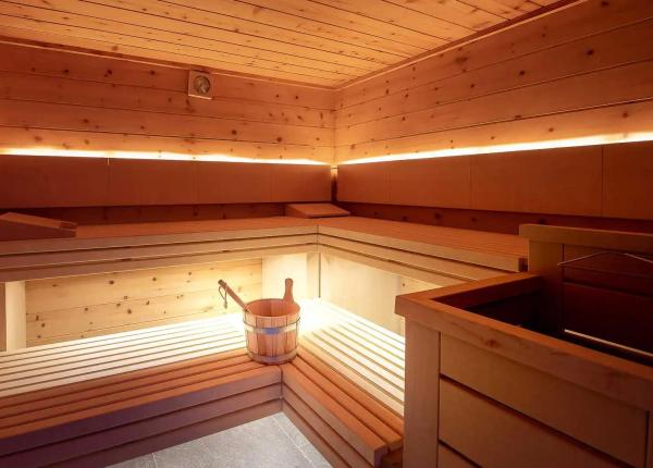 Sauna in legno con secchio e mestolo, illuminazione calda.