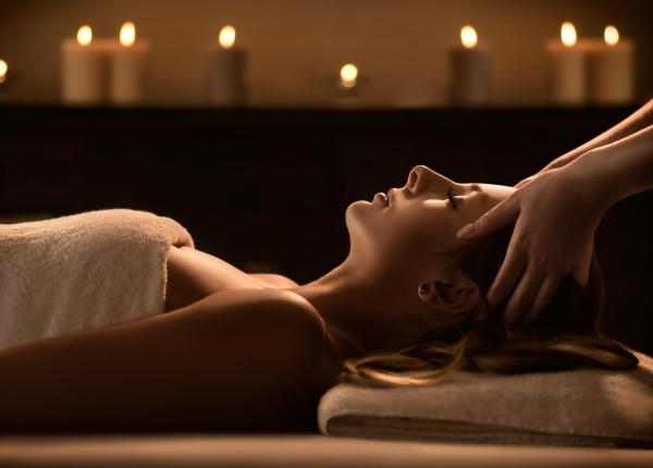 Woman receiving a relaxing massage with lit candles.