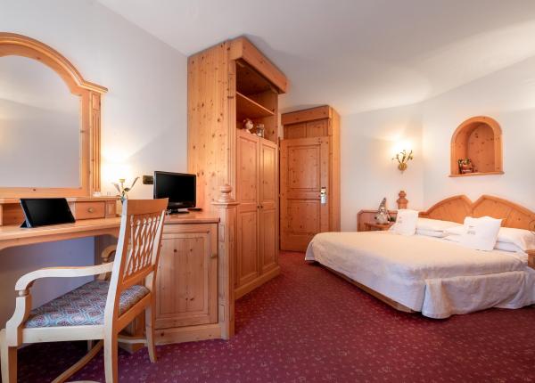 Cozy room with wooden furniture, double bed, and desk with mirror.