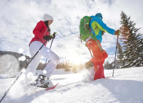 Zwei Personen wandern im Schnee mit Schneeschuhen.