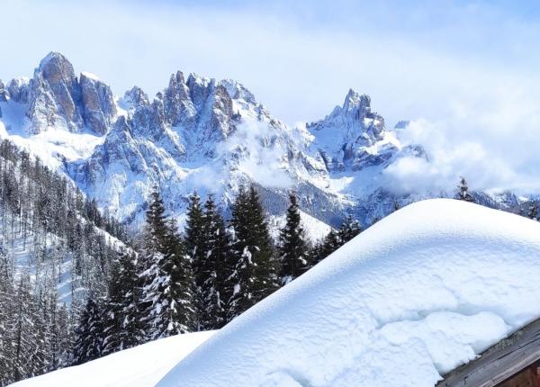 Snowy mountains and wooden chalet under a blue sky.