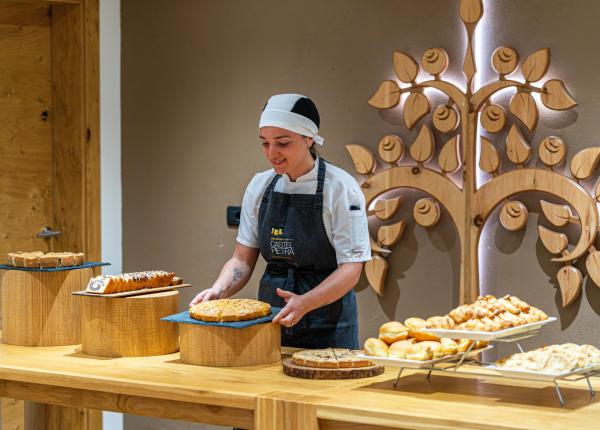 Pasticcera con dolci su tavolo di legno decorato.