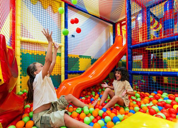 Bambini giocano felici in una piscina di palline colorate.