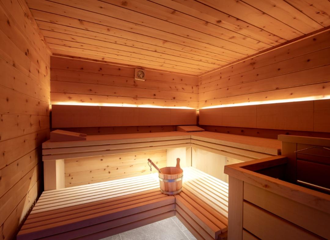 Una sauna in legno con illuminazione soffusa e un secchio di legno.