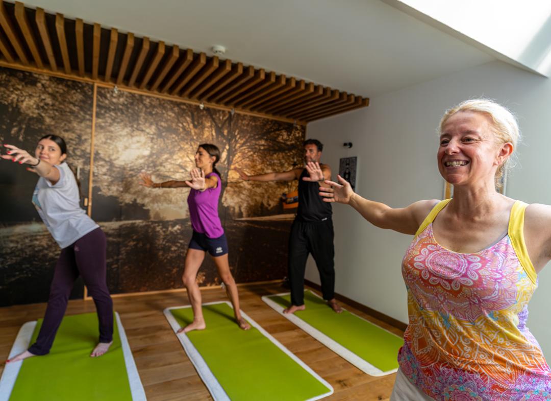 Sala yoga con tappetini, cuscini e parete decorata con albero.