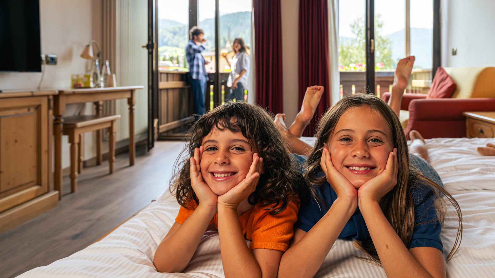 Camera accogliente con arredi in legno, scrivania, letto matrimoniale e dispositivi elettronici.