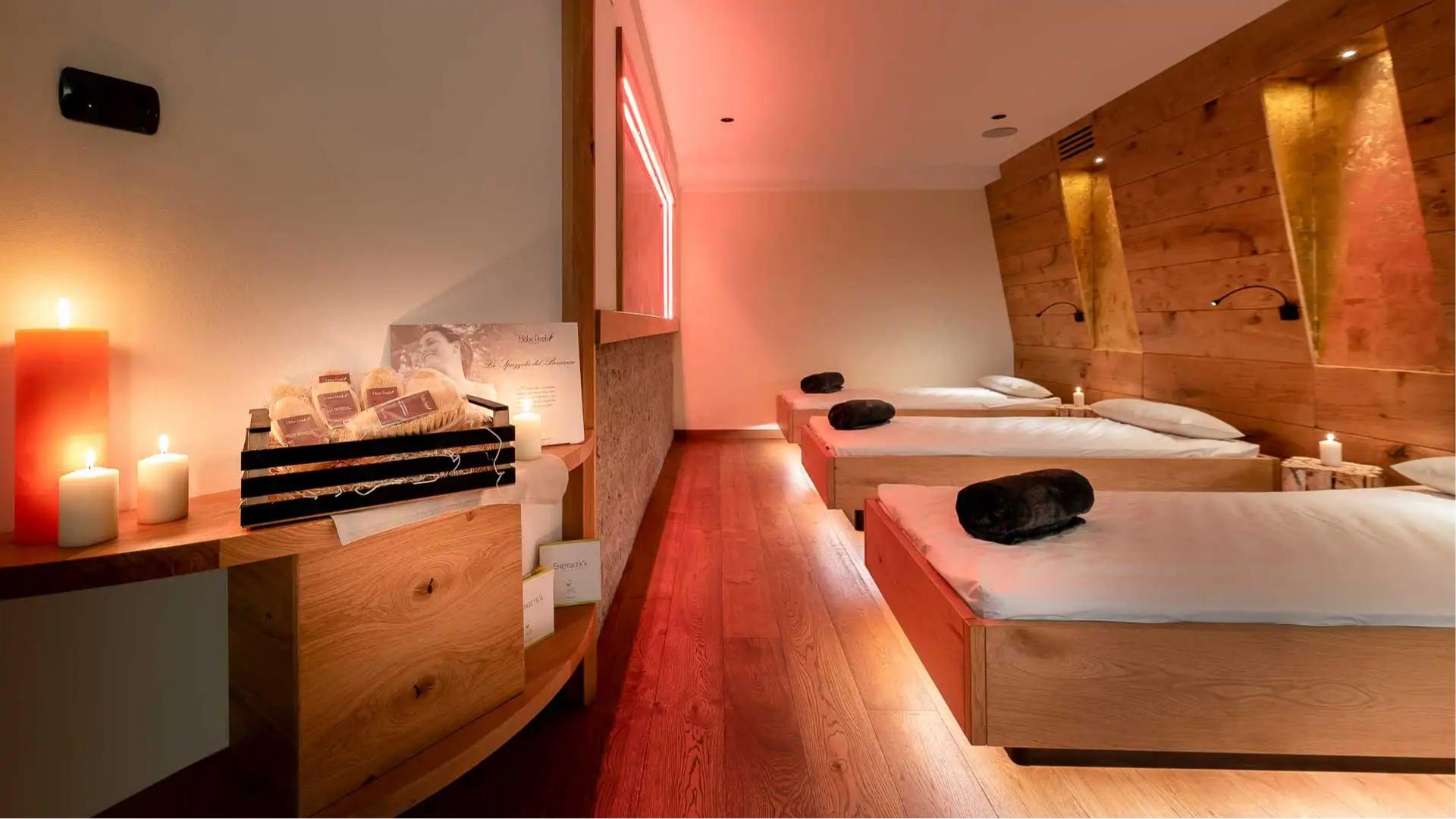 Sala relax con letti in legno, candele accese e atmosfera calda.