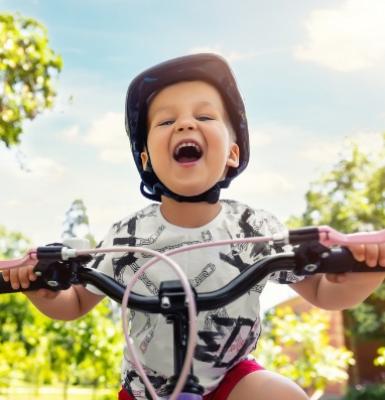 Un bambino felice che pedala su una bicicletta con un casco protettivo.