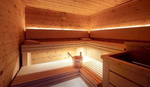 Una sauna in legno ben illuminata con secchio e mestolo.