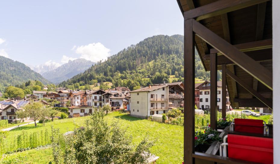 Camera spaziosa con travi in legno, divano rosso e arredi classici.