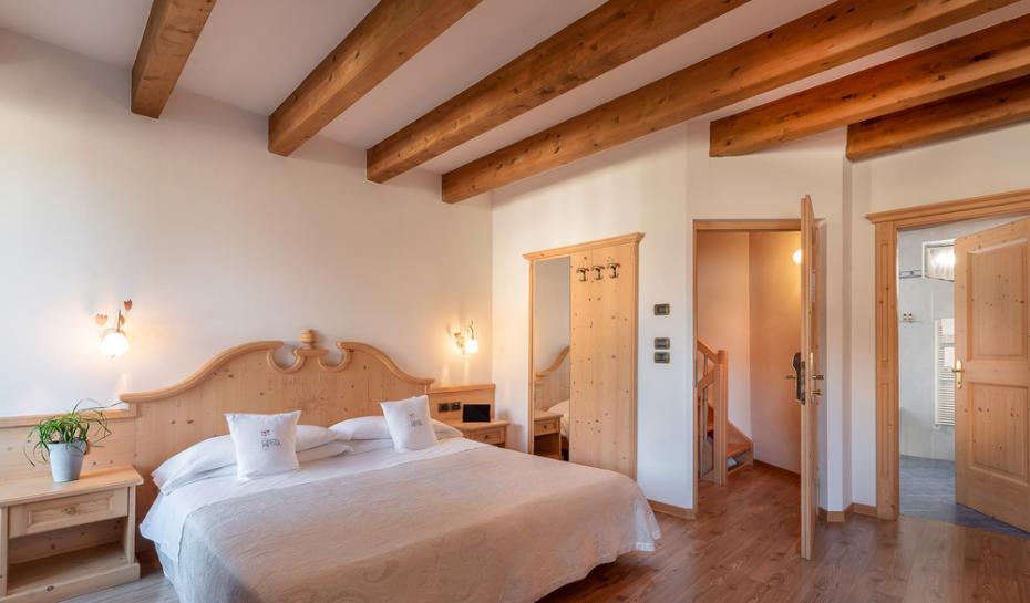 Camera accogliente con letto in legno, lampada decorativa e pianta sul comodino.