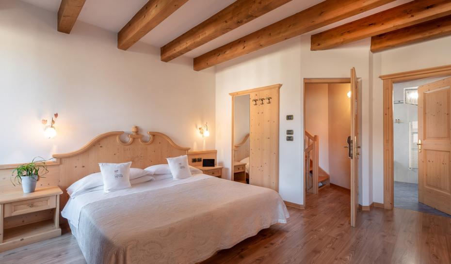 Camera accogliente con letto matrimoniale, decorazioni in legno e illuminazione calda.