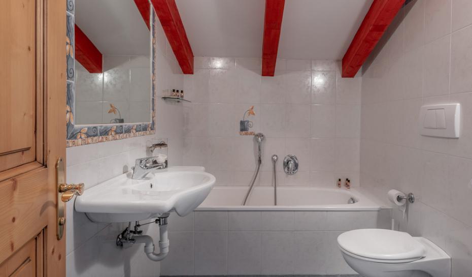 Bathroom with bathtub, sink, and exposed red beams.